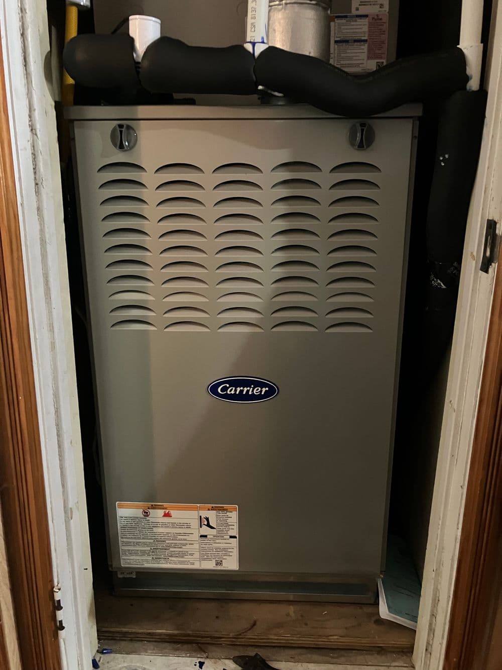 Carrier heating unit installed in a closet, showcasing vents and safety labels.