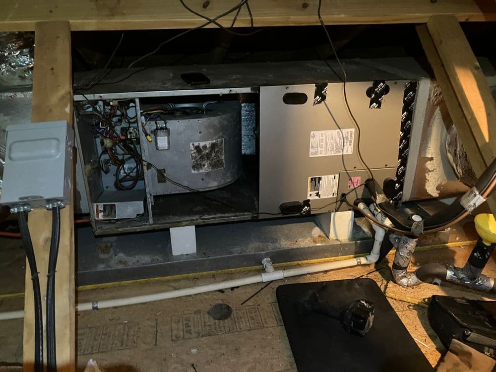 Electrical equipment in attic with wires and ducts visible, showcasing HVAC system setup.