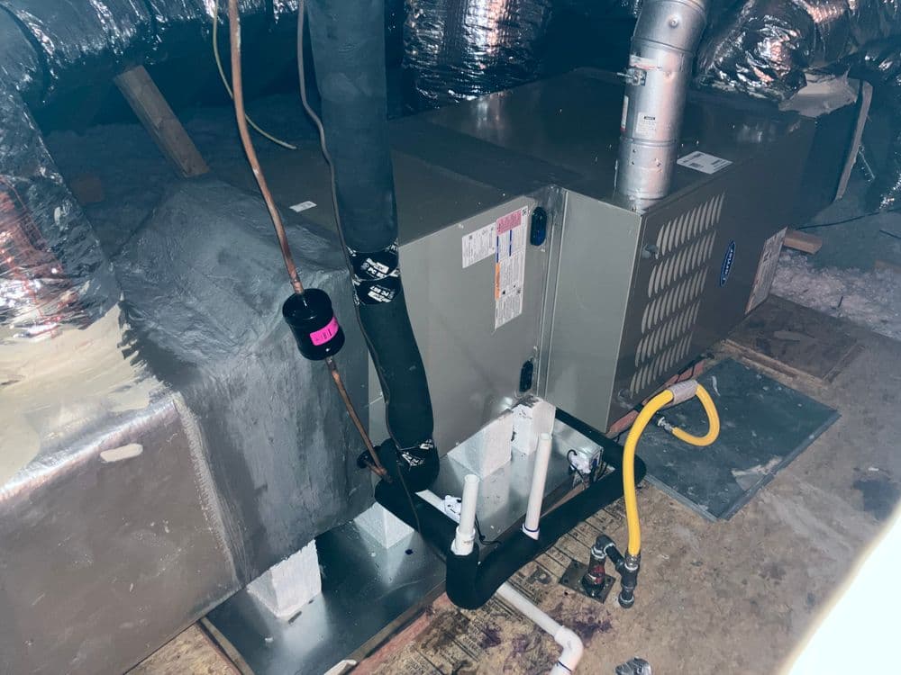 HVAC system in attic with ducts and pipes, showcasing installation and components.