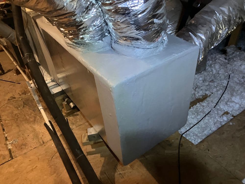 Insulated ductwork with silver tape in an attic, showcasing HVAC installation details.