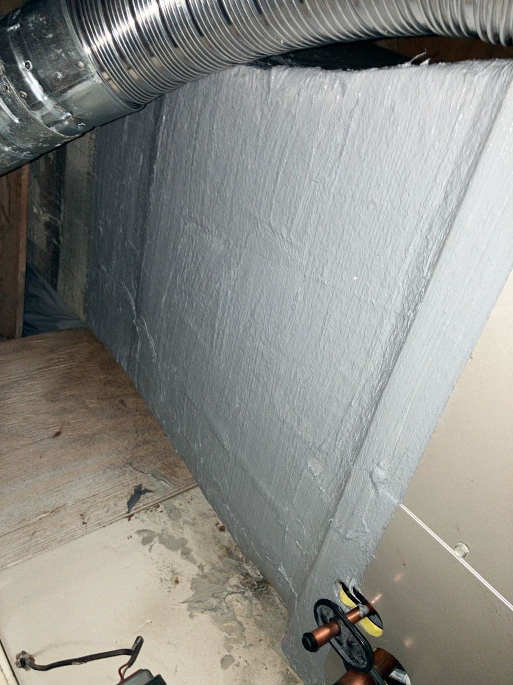 Insulated HVAC ductwork with gray foam board in a basement setting.