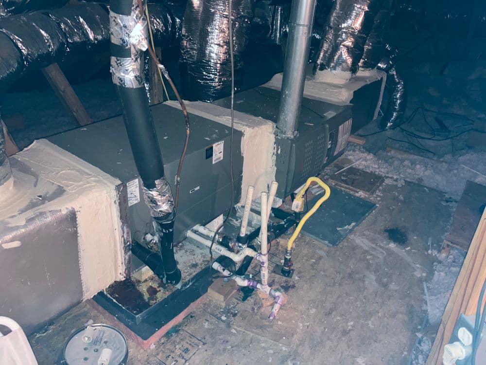 Heating and cooling systems in an attic with ductwork and insulation visible.