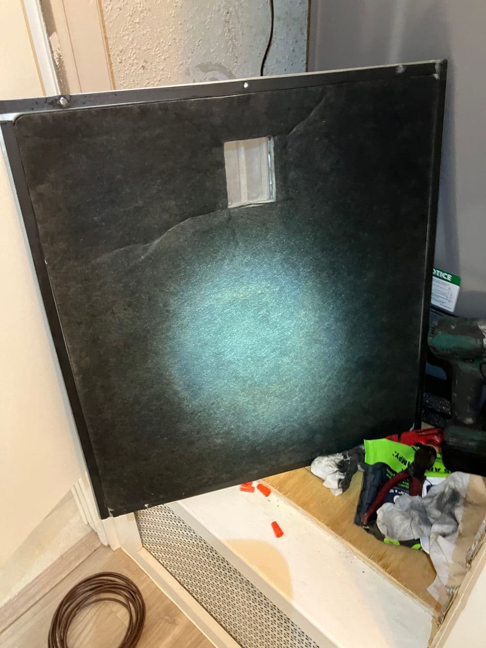 Backlit panel being installed near tools and supplies in a home renovation project.