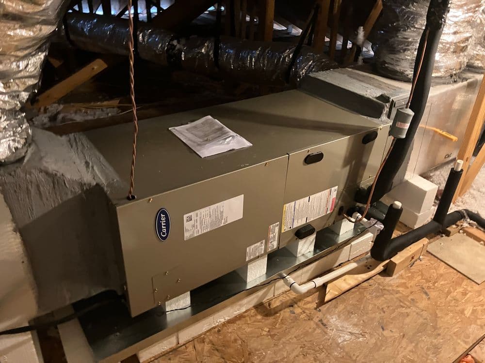 Carrier HVAC unit installed in an attic, showcasing ductwork and insulation.