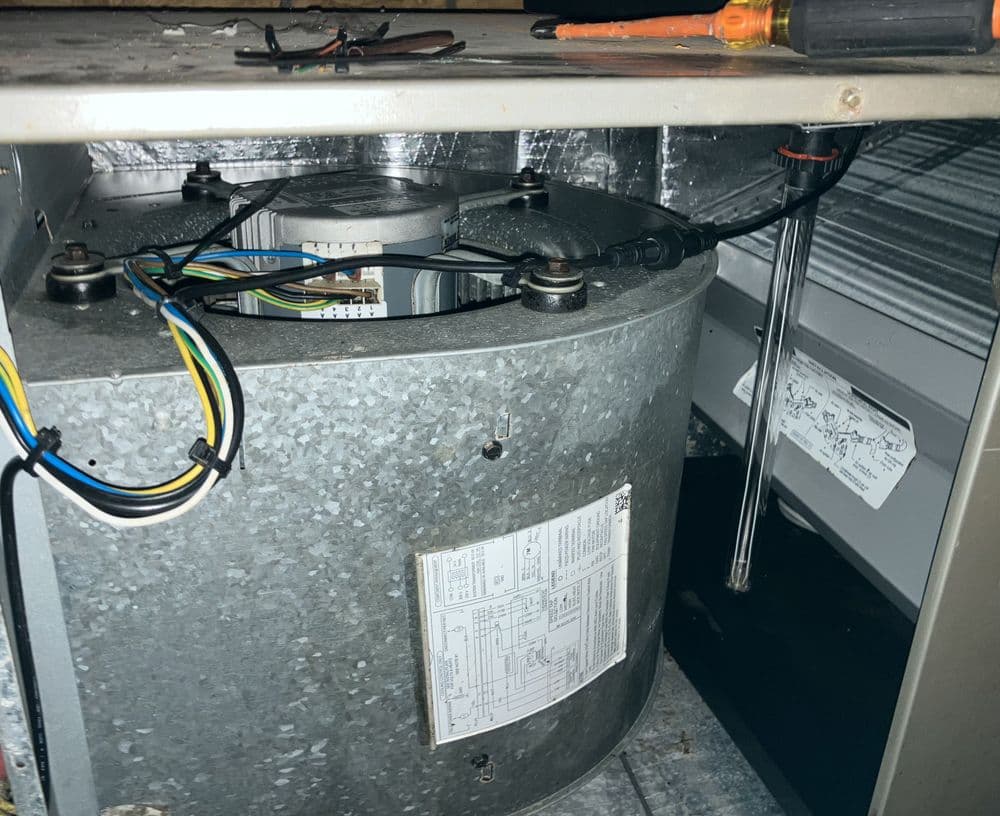 Close-up of HVAC unit showing motor assembly and wiring connections. Tools nearby.