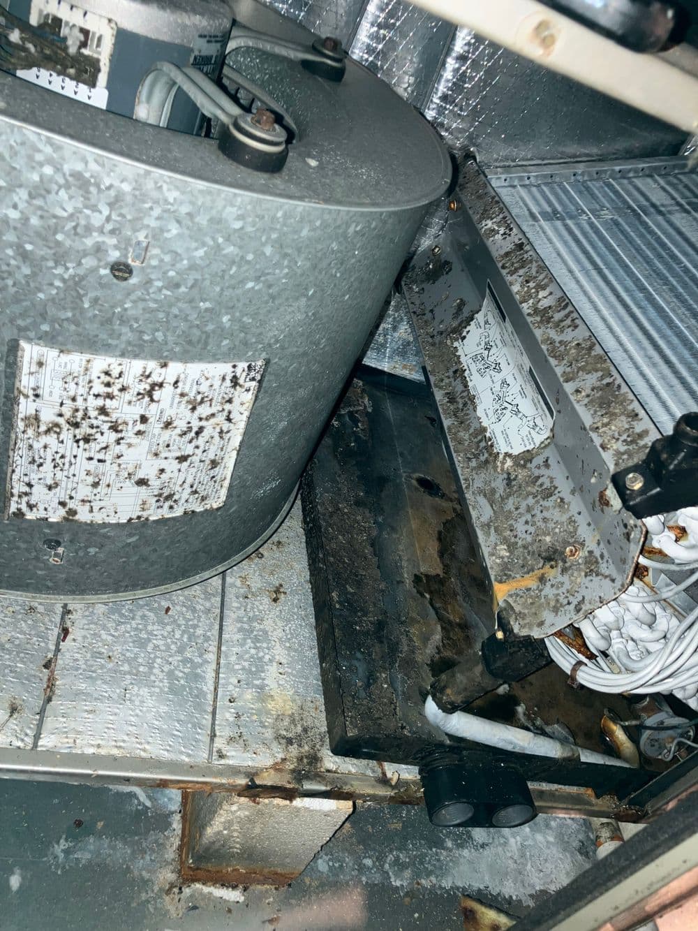 Old industrial cooling unit showing rust and dirt on components and surrounding area.